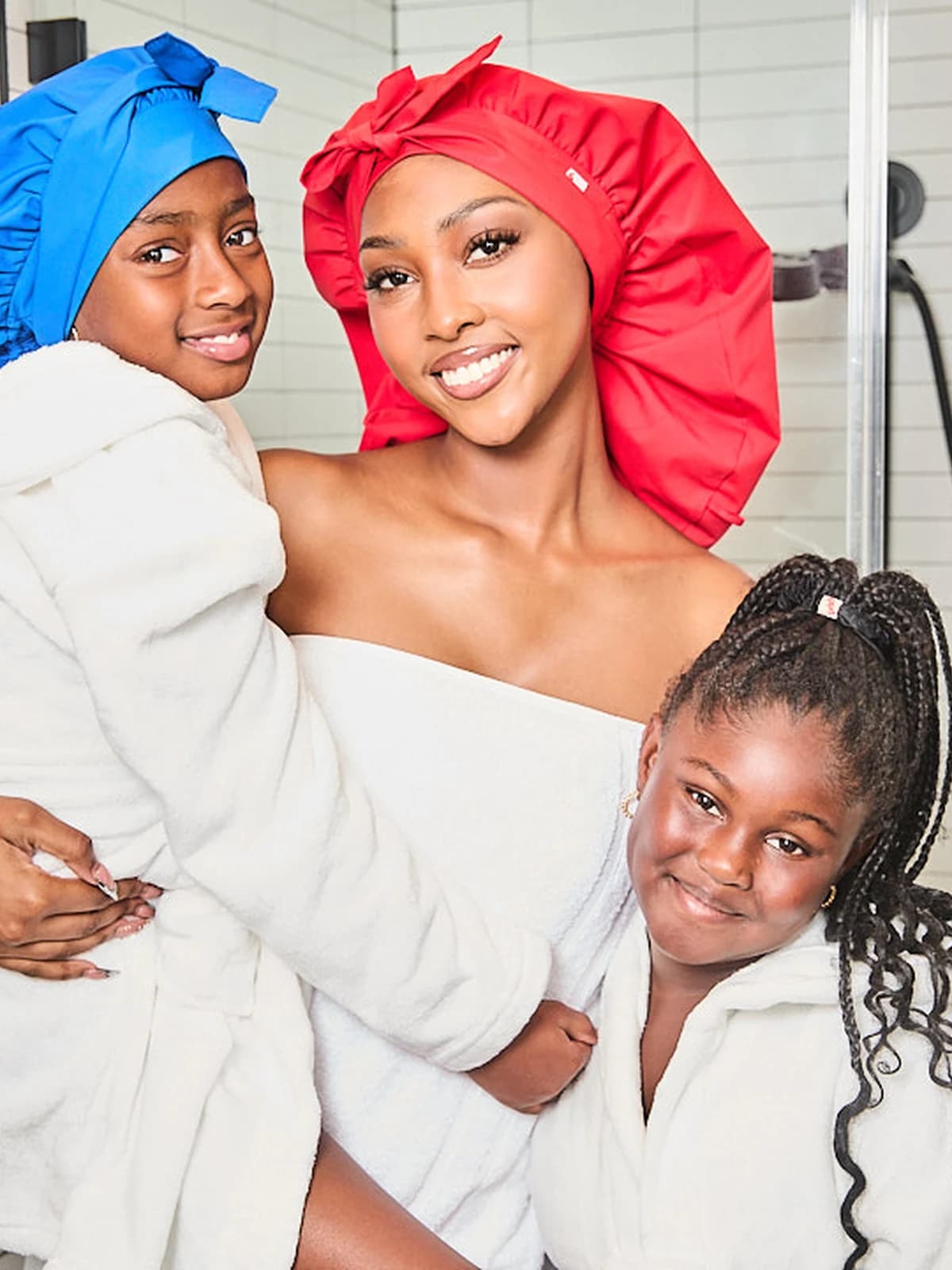 A family wearing Wrappd shower bonnets in cobalt and crimson